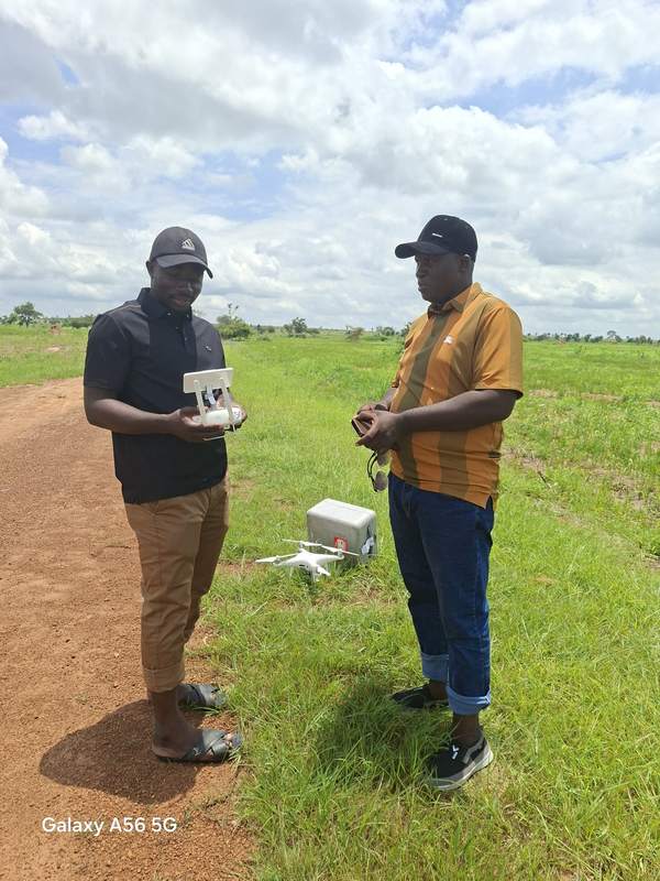 Brains Gaude and Professor Gani standing in a field with a survey drone and its controller